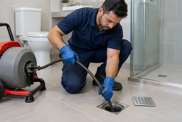 Profissional realizando desentupimento de ralo em um banheiro em Passos.